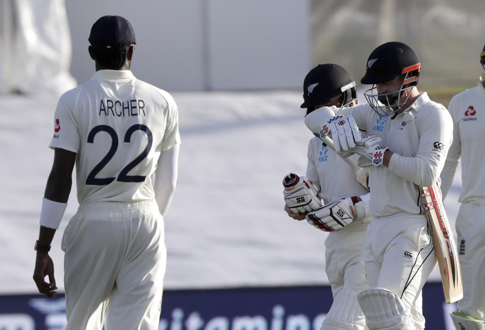 England's Jofra Archer, left, watches as not out batsman New Zealand's Henry Nicholls, right, and BJ Watling walk from the field at the close of play during play on day two of the first cricket test between England and New Zealand at Bay Oval in Mount Maunganui, New Zealand, Friday, Nov. 22, 2019. (AP Photo/Mark Baker)