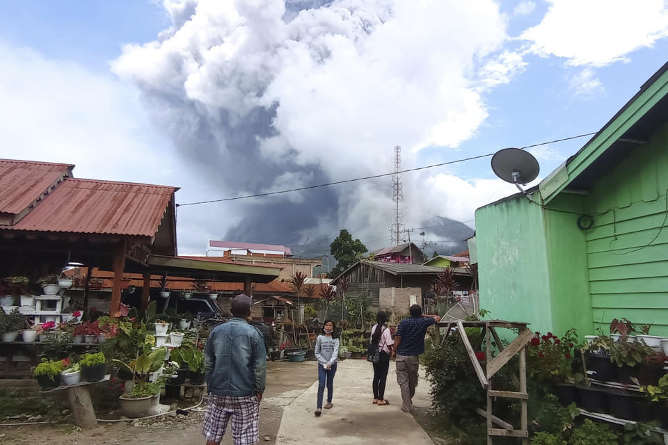 People watch as Mount Sinabung spews volcanic materials during an eruption in Karo, North Sumatra, Indonesia. Wednesday, July 28, 2021. The rumbling volcano on Indonesia’s Sumatra island on Wednesday shot billowing columns of ash and hot clouds down its slopes. (AP Photo/Sastrawan Ginting)