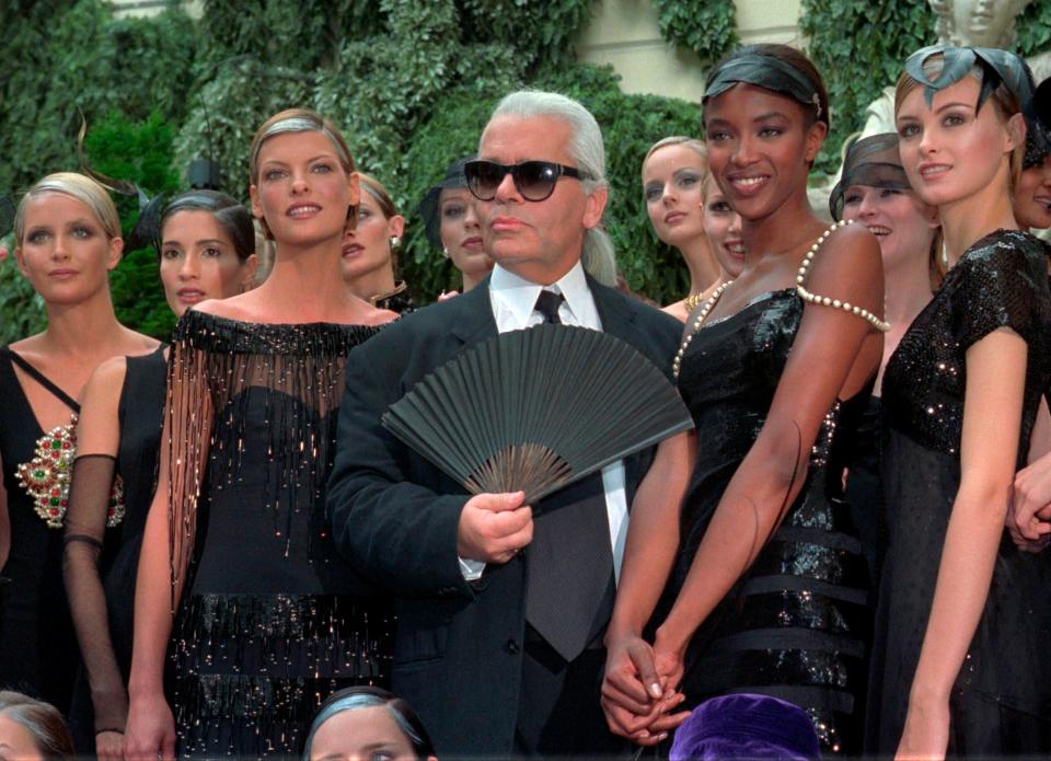 In this July 9, 1996, file photo, Karl Lagerfeld is surrounded by Linda Evangelista, left, Naomi Campbell, right, and other models after the presentation of his 1996-97 Fall/Winter haute couture fashion collection for Chanel in Paris.