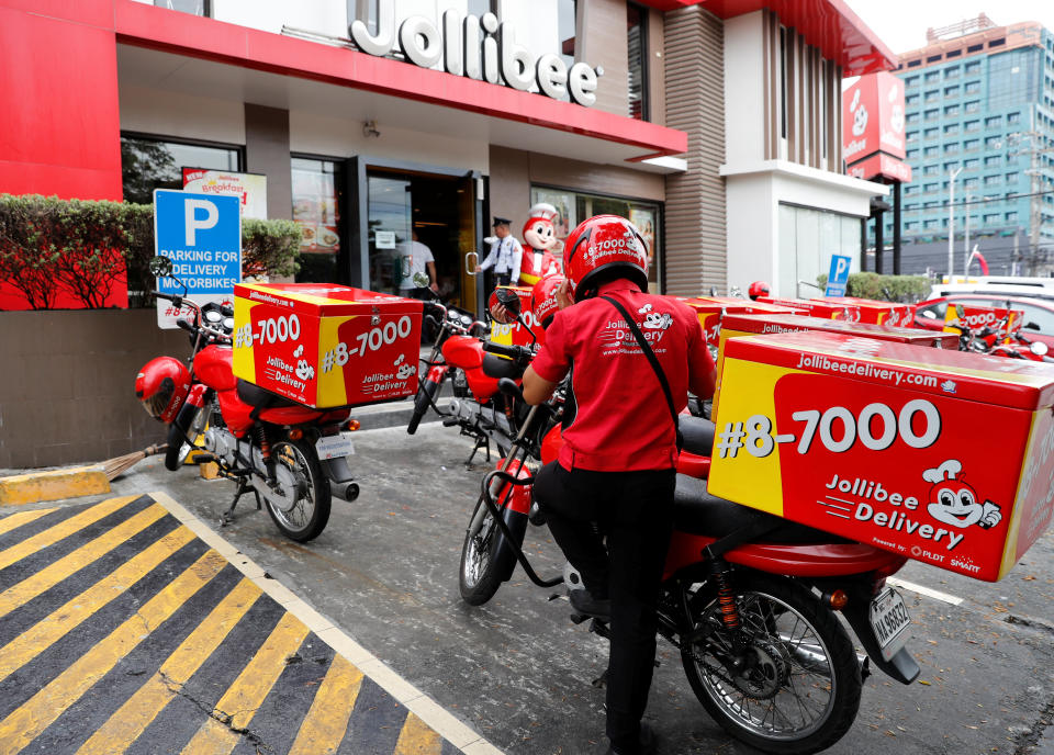 FILE PHOTO: A Jollibee fastfood chain delivery worker boards a motorycle in Las Pinas, Metro Manila in Philippines June 7, 2018. REUTERS/Erik De Castro