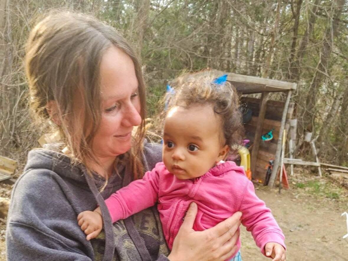 Lisa Sharpe holds one of Emily Petrini-Woolley's children in this photo submitted by her longtime friend. Sharpe was found dead inside a home in Eganville, Ont., on Jan. 25, and her son has been charged with second-degree murder. (Submitted/Emily Petrini-Woolley - image credit)