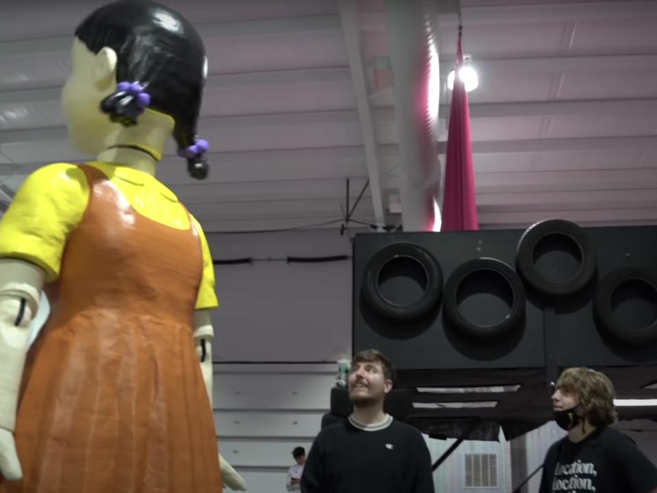 Matthew Beem and MrBeast standing in front of a giant ''Squid Game' doll.