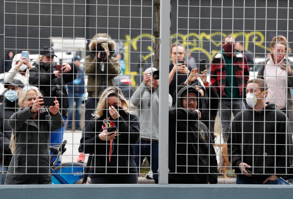 New Yorkers peer through a fence at Pier 90, recording the moment on their cell phones, during the arrival of the USNS Comfort, Monday, March 30, 2020.