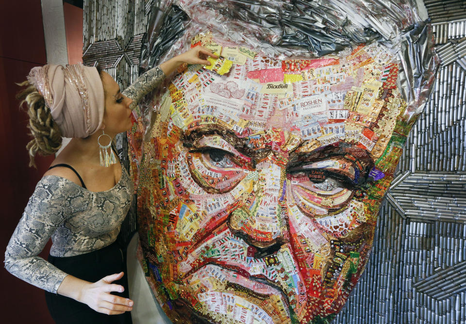 Ukrainian artist Dasha Marchenko adds a chocolate wrapper to her portrait of Ukraine's President and chocolate tycoon Petro Poroshenko at her studio in Kiev, Ukraine, Thursday, March 28, 2019. The artist bought around 20 kilograms of chocolate using the wrappers to create his face. The framework was constructed using 4000 gun shells from battlefields in the country’s east that has been hit by conflict with Russia-backed separatists since 2014. Poroshenko is running for the second term as president in elections to be held on March 31. (AP Photo/Efrem Lukatsky)