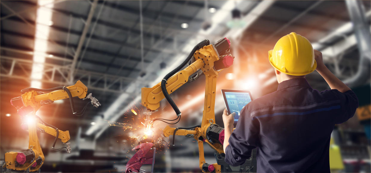 An engineer checks and control robot arms in a manufacturing unit. Photo: Getty