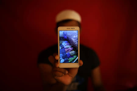 Islamic teacher Mohammed Younus holds a mobile phone on May 20, 2018 showing a video of what he says are the bodies of Rohingya Muslims killed by government forces in Kyauk Pan Du, Myanmar, on August 28, 2017. REUTERS/Mohammad Ponir Hossain/Files