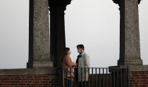 A man and a woman wearing face masks talk as they stand on the Ponte Coperto (Covered bridge), also known as Ponte Vecchio (Old Bridge), a brick and stone arch bridge over the Ticino River, in Pavia, some 40 kilometers (24 miles) away rom Milan, Italy, Friday, Oct. 30, 2020. (AP Photo/Antonio Calanni)