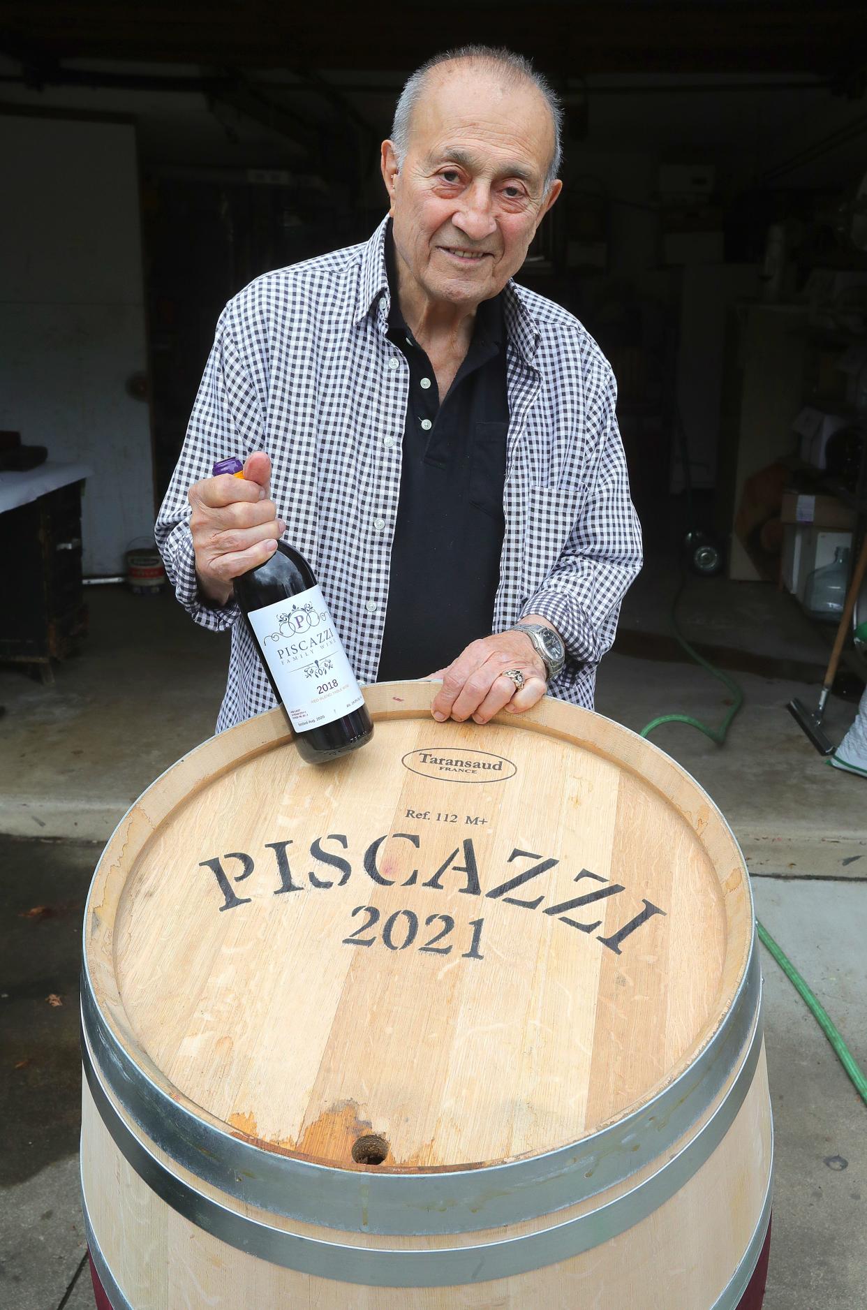 Joe Piscazzi holds a bottle of his Piscazzi Family red blend May 7 near a new French oak barrel to age this year's wine in Cuyahoga Falls.