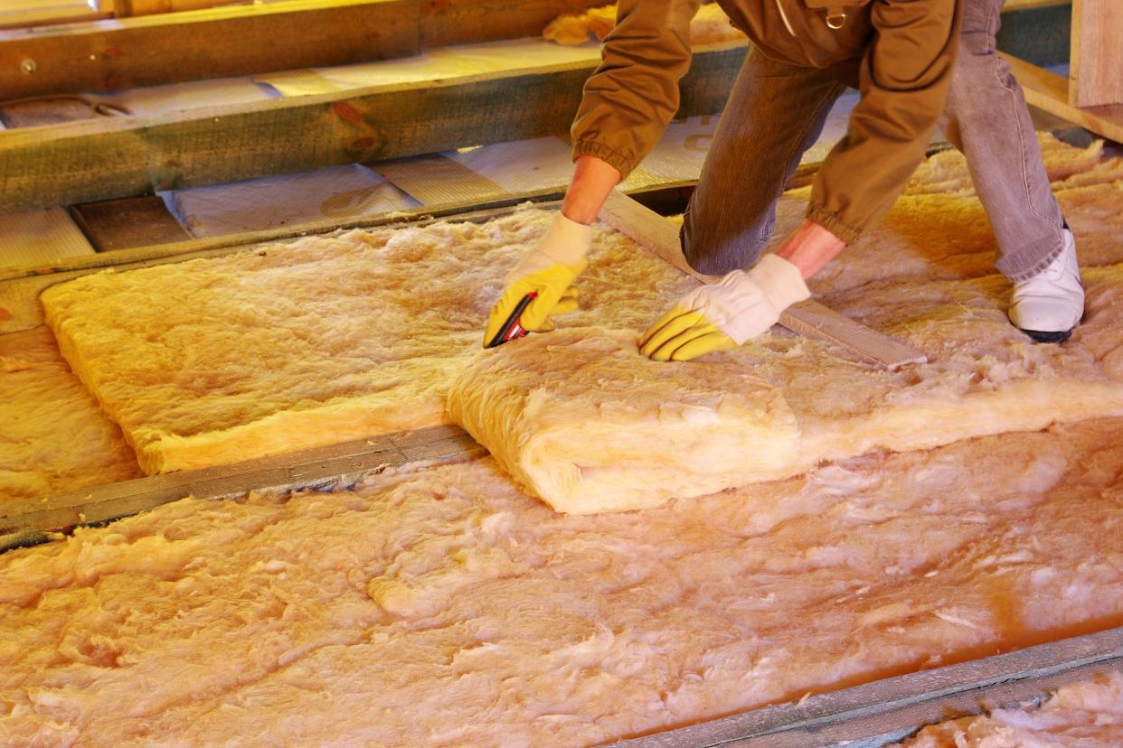 construction worker thermally insulating house attic with glass wool