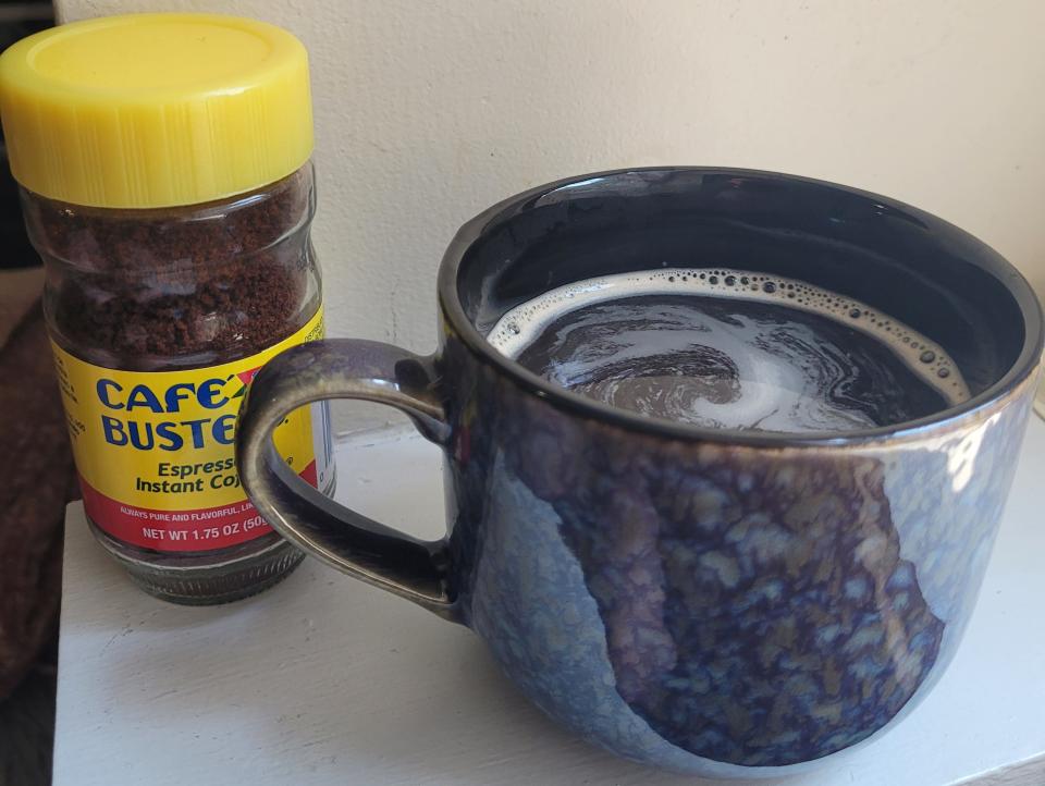 cafe bustelo instant coffee next to a cup of prepared instant coffee