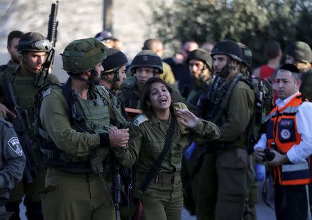 An Israeli female soldier reacts at the scene where a Palestinian stabbed and killed an Israeli soldier at a petrol station before he was shot dead by soldiers near the West Bank village of Khirbit Al-Misbah between Jerusalem and Tel Aviv November 23, 2015. REUTERS/Ammar Awad