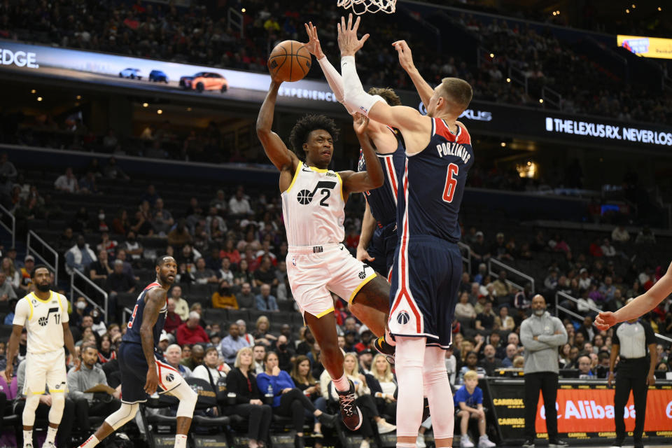 Utah Jazz guard Collin Sexton (2) goes to the basket against Washington Wizards center Kristaps Porzingis (6) and forward Corey Kispert during the first half of an NBA basketball game Saturday, Nov. 12, 2022, in Washington. Kispert was charged with a foul on the play. (AP Photo/Nick Wass)