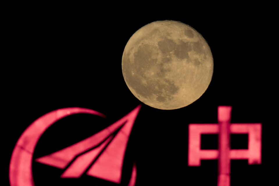 In this photo taken Tuesday, Nov. 15, 2016, the supermoon rises over a logo for a Chinese state owned enterprise with part of the word for "China" in Beijing. China's Nov. 24, 2020, trip to the moon and, presumably, back is the latest milestone in the Asian powerhouse's slow but steady ascent to the stars. (AP Photo/Ng Han Guan, File)