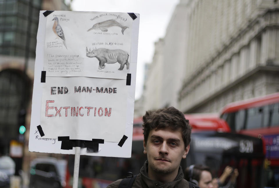 An Extinction Rebellion climate change protester holds a banner in central London, Thursday, April 25, 2019. The non-violent protest group, Extinction Rebellion, is seeking negotiations with the government on its demand to make slowing climate change a top priority. (AP Photo/Matt Dunham)