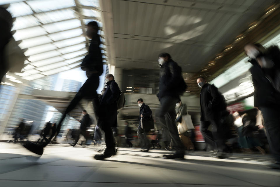 FILE - Commuters wearing face mask make their way during a rush hour on Jan. 8, 2021 in Tokyo. Wages are rising in Japan more than they have in decades, at least for some workers. But so are prices, leaving many people feeling they must scrimp more than ever. (AP Photo/Eugene Hoshiko, File)