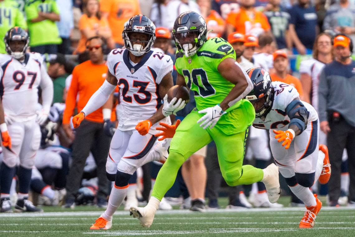 Seattle Seahawks running back Rashaad Penny (20) runs away from a tackle attempt by Denver Broncos linebacker Jonas Griffith (50) during the second quarter of an NFL game on Monday, Sept. 12, 2022, at Lumen Field in Seattle.