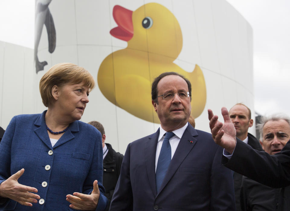 Chancellor Angela Merkel, left, and French President Francois Hollande walk past a giant rubber duck on the facade of a building during their visit of the old town of Stralsund, northern Germany, Saturday, May 10, 2014, the second day of Hollande's two days visit to Merkel's scenic home constituency on the Baltic coast . One of the main talking points is expected to be over whether the European Union should impose further sanctions on Russia, for its involvement in the Ukraine crisis. (AP Photo/Gero Breloer)