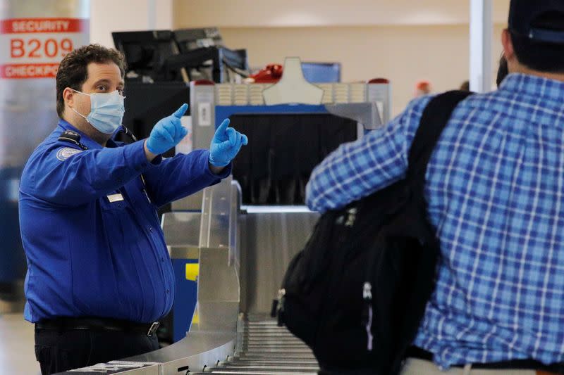 A TSA officer wears a mask and gloves at Logan International Airport in Boston