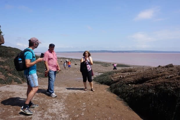 Daniel Bourgault, left, El Hadi Cherfouh and Nacera Bellila stand by the Hopewell Rocks in New Brunswick, where the bottle was found. 