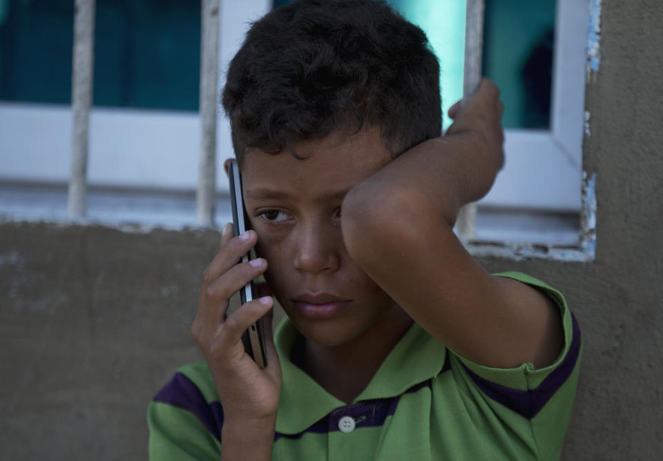 In this Dec. 11, 2018 photo, 10-year-old Greider wipes away tears as he speaks with his mother Emili Espinoza, outside his uncle's home in Punto Fijo, Venezuela. Espinoza said her children first begged her not to leave to Colombia. But then they started going even more hungry, sometimes passing two or three days without eating. When she approached the subject, Greider, her oldest, said she could go. (AP Photo/Fernando Llano)