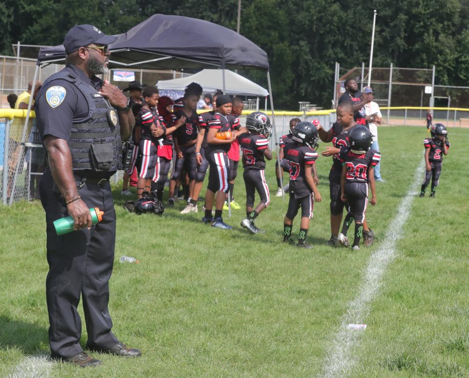 Akron police detective Sean Taylor keeps an eye on the pee wee football action Sunday at Erie Island Park.