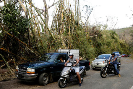 Motorists and motorcyclists wait for soldiers to clear the road of debris left by Hurricane Maria on a road near Guayama, Puerto Rico October 12, 2017. REUTERS/Lucas Jackson