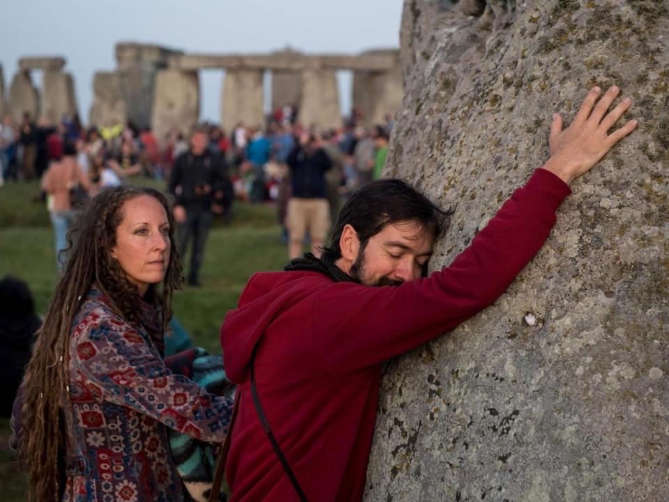 Revellers touch the Heel stone as people watch the sun rise (AFP/Getty Images)