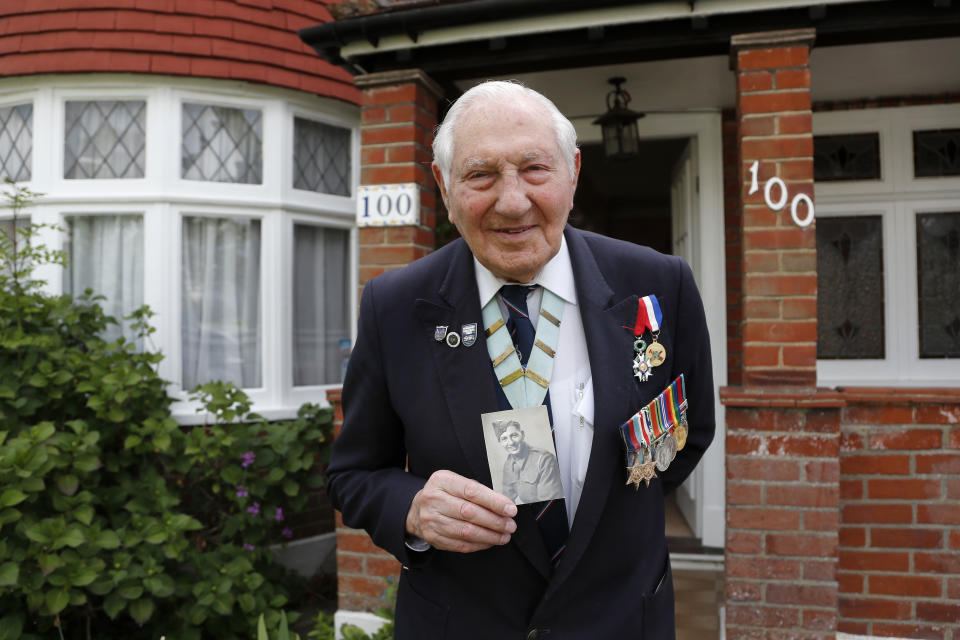World War II Veteran Mervyn Kersh poses in front of his house with a picture of himself in uniform in London, Monday, May 4, 2020. Kersh likes to joke that he was probably the last British soldier to learn the Nazis had surrendered. Pvt. Kersh, who was with forces that liberated the Bergen-Belsen concentration camp, had been ordered to return to England for deployment to Japan so he was on a blacked-out train crossing Europe when the celebrations began. By the time he got to London, the party was over.(AP Photo/Frank Augstein)