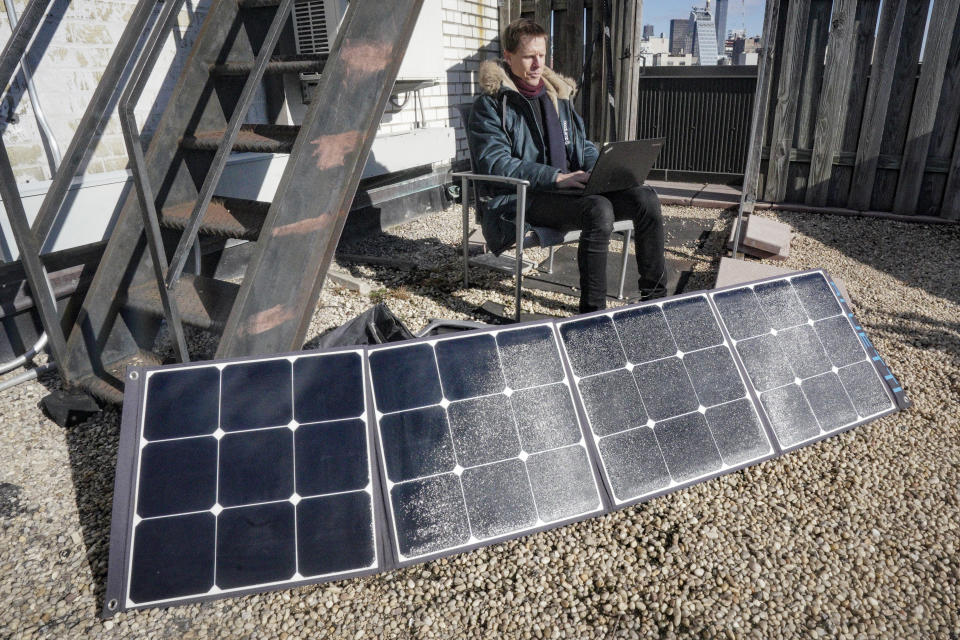 Josh Spodek trabaja en su computadora portátil mientras se carga con un kit portátil de paneles solares instalado en la azotea de su edificio de apartamentos en Greenwich Village, Nueva York, el martes 24 de enero de 2023. sus esfuerzos por prescindir de los envases cambiaron su mentalidad de forma tan drástica que le llevaron a reducir su consumo eléctrico casi a cero. Incluso se deshizo del refrigerador, que, según él, era la mayor fuente de consumo eléctrico de su apartamento. (AP Foto/Bebeto Matthews)