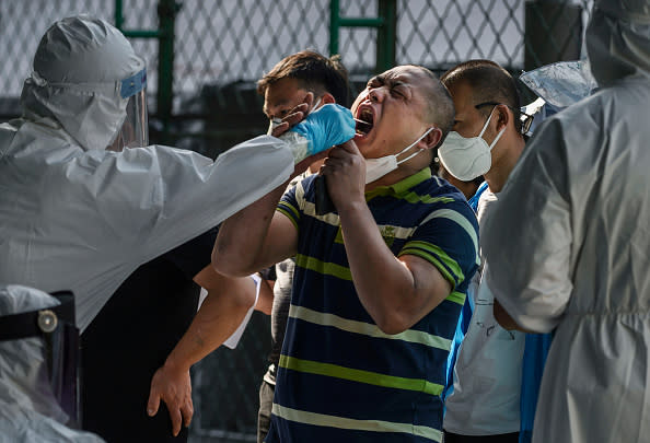 A Chinese epidemic control worker wears a protective suit and mask while performing a nucleic acid test for COVID-19 on a man who has had contact with the Xinfadi Wholesale Market or someone who has, at a testing centre in Beijing, China.