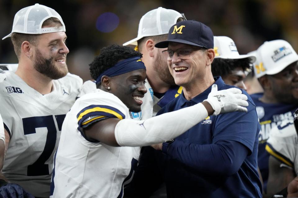 Michigan defensive back Mike Sainristil (0) celebrates with head coach Jim Harbaugh after the Big Ten championship.