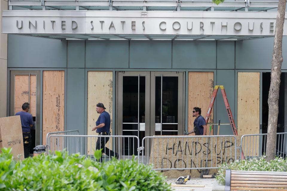 People work outside of a United States Courthouse at the Ronald V. Dellums Federal Building after protests over the Memorial Day death of George Floyd in Oakland, Calif., Saturday, May 30, 2020.