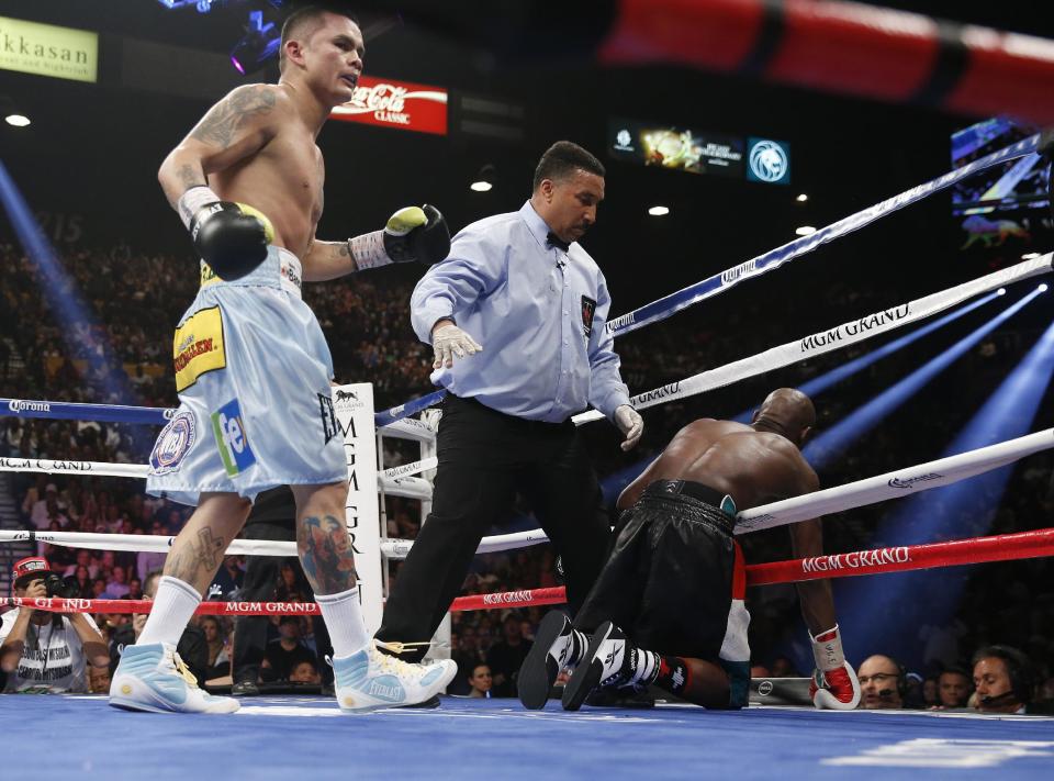 Marcos Maidana, left, from Argentina, watches after knocking Floyd Mayweather Jr. through the ropes in their WBC-WBA welterweight title boxing fight Saturday, May 3, 2014, in Las Vegas. At center is referee Tony Weeks. (AP Photo/Eric Jamison)