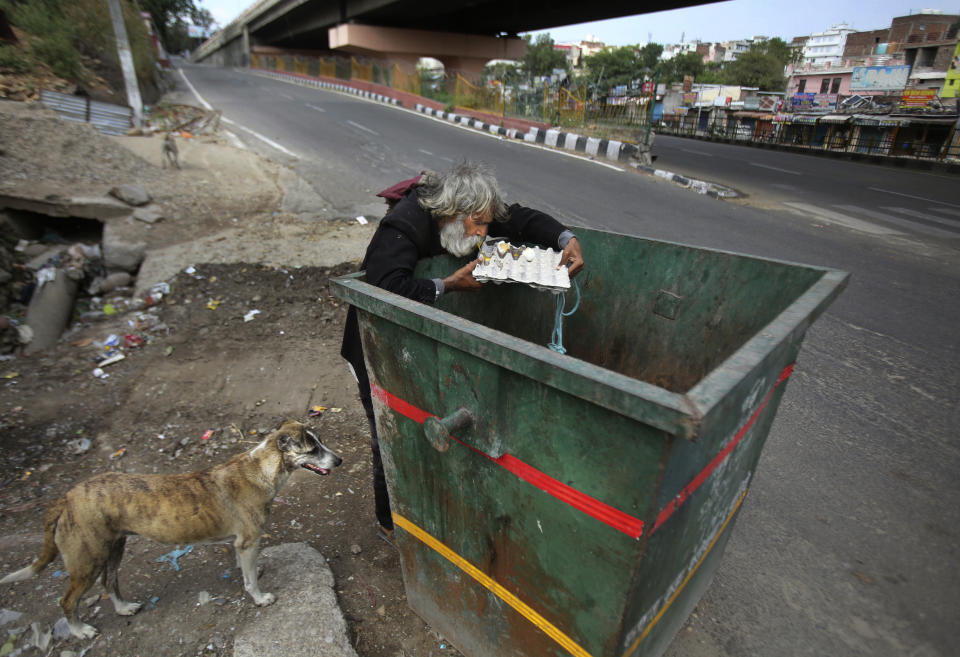 An Indian homeless man eats eggs discarded in a garbage bin during lockdown to curb the spread of new coronavirus on the outskirts of Jammu, India, Sunday, May 10, 2020. India's lockdown entered a sixth week on Sunday, though some restrictions have been eased for self-employed people unable to access government support to return to work. (AP Photo/Channi Anand)