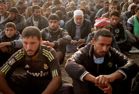 Newly displaced men sit at a check point in Qayyara, east of Mosul. REUTERS/Goran Tomasevic