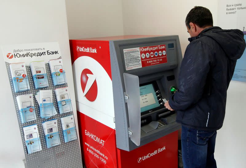 FILE PHOTO: A man uses an ATM bank machine at a branch office of UniCredit Bank in Krasnoyarsk, Siberia
