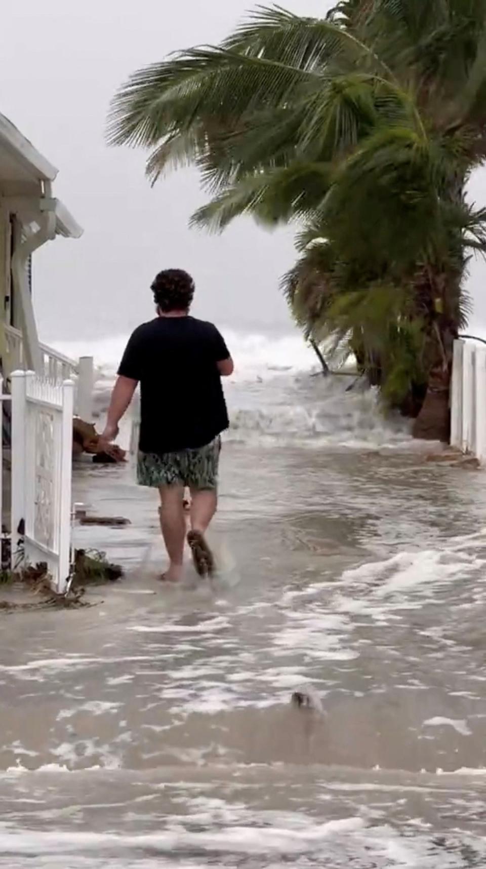 <p>A man walks as water flows past the walls of the beach near building structures as Hurricane Helene approaches at Indian Shores, Florida, U.S</p> (via REUTERS)