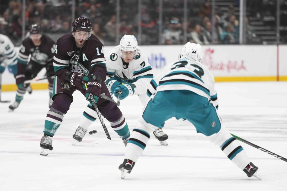 Anaheim Ducks' Adam Henrique (14) is pressured by San Jose Sharks' Calen Addison (33) and Nico Sturm (7) during the first period of an NHL hockey game Sunday, Nov. 12, 2023, in Anaheim, Calif. (AP Photo/Jae C. Hong)