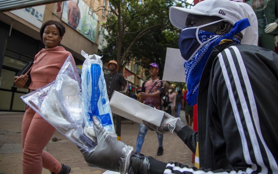 A man wearing a face mask sells masks and gloves in downtown Johannesburg, South Africa, Friday, March 20, 2020. Anxiety rose in Africa's richest nation Friday as South Africa announced coronavirus cases jumped to 202, the most in the sub-Saharan region, while the country's largest airport announced that foreigners would not be allowed to disembark. And state-owned South African Airways suspended all international flights until June. (AP Photo/Themba Hadebe)