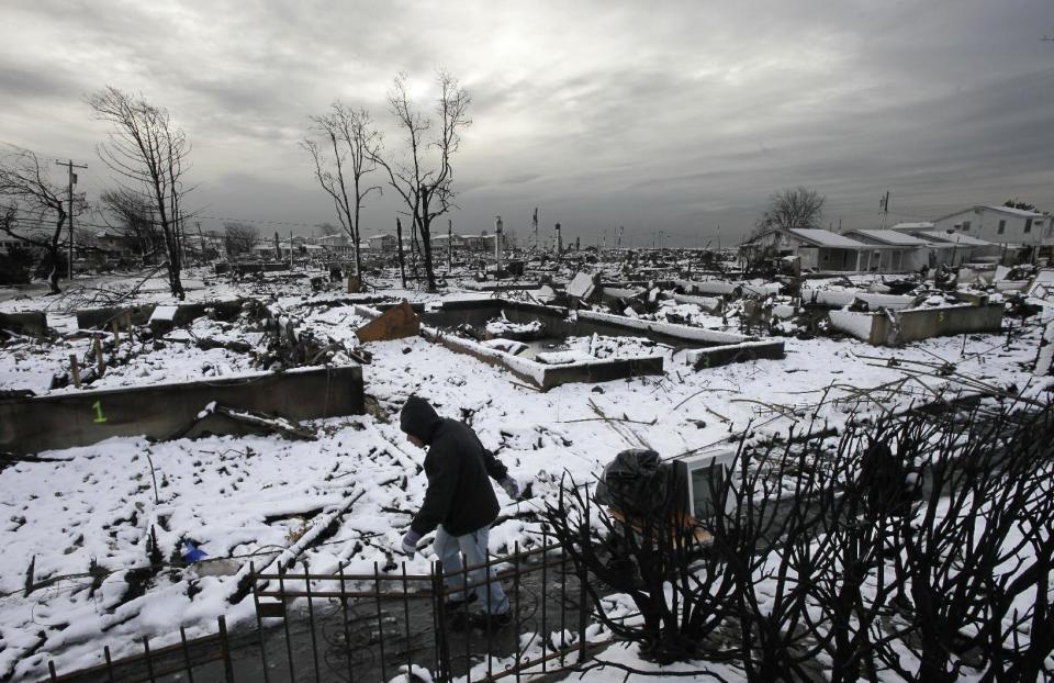 Damon Rasinya carts debris from his family home past the fire-scorched landscape of Breezy Point after a Nor'easter snow, Thursday, Nov. 8, 2012 in New York. The beachfront neighborhood was devastated during Superstorm Sandy when a fire pushed by the raging winds destroyed many homes. (AP Photo/Mark Lennihan)