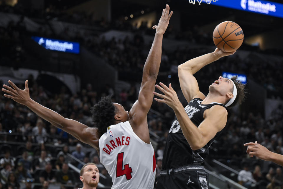 San Antonio Spurs' Zach Collins, right, goes to the basket against Toronto Raptors' Scottie Barnes (4) during the first half of an NBA basketball game, Sunday, Nov. 5, 2023, in San Antonio. (AP Photo/Darren Abate)