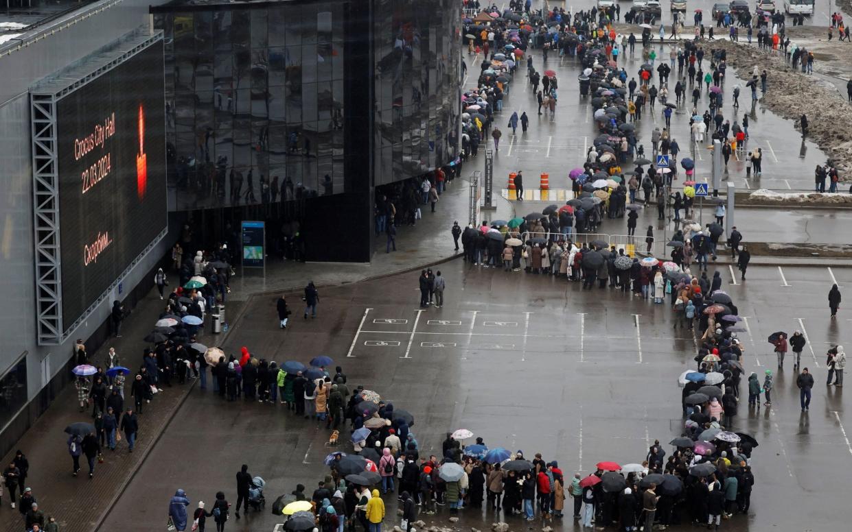 People line up to lay flowers at a makeshift memorial to the victims of a shooting attack set up outside the Crocus City Hall concert venue in Moscow.