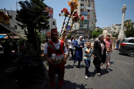 A Palestinian man sells juice as people walk in Ramallah, in the Israeli-occupied West Bank