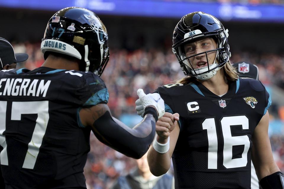 Jacksonville Jaguars tight end Evan Engram (17), left, and Jacksonville Jaguars quarterback Trevor Lawrence (16) fist bump during the NFL football game between Denver Broncos and Jacksonville Jaguars at Wembley Stadium in London, Sunday, Oct. 30, 2022. (AP Photo/Ian Walton)