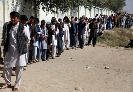 Afghan men line up at a polling station as they wait to cast their votes in Kabul