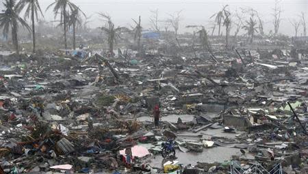 Survivors stand among debris and ruins of houses destroyed after Super Typhoon Haiyan battered Tacloban city in central Philippines November 10, 2013. REUTERS/Erik De Castro