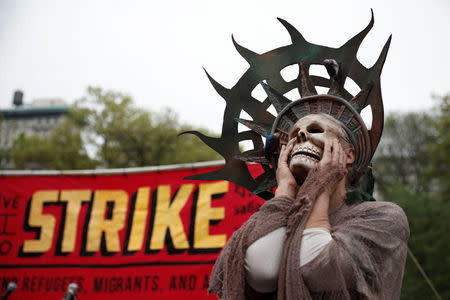 A woman wearing a costume stands during a May Day protest in New York, U.S. May 1, 2017. REUTERS/Mike Segar