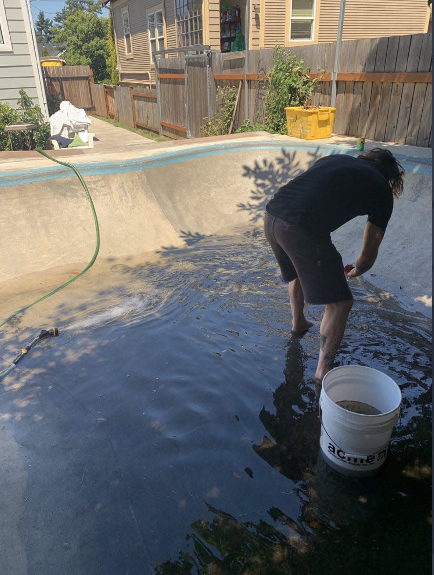 A man filling a pool with water in a backyard.