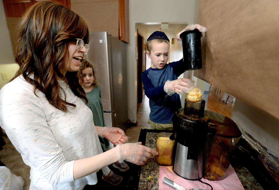 Gershon Turen, 6, right, makes orange juice for Passover with his mother Sara, left, and little sister Shaina, 4, at their Springfield home on April 4, 2023.