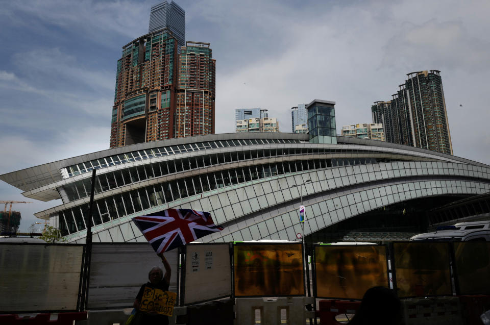 A woman waves a British flag outside the Western Kowloon Station during a protest against the opening ceremony of the Hong Kong Express Rail Link in Hong Kong, Saturday, Sept. 22, 2018. Hong Kong has opened a new high-speed rail link to inland China that will vastly decrease travel times but which also raises concerns about Beijing's creeping influence over the semi-autonomous Chinese region. (AP Photo/Vincent Yu)